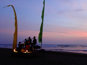 A live band plays on Seminyak beach as the sun sets. The dark hides the rubbish...